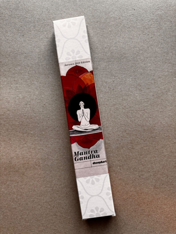 Räucherstäbchen-Verpackung 'Mantra Gandha' von dhoop&art, Autumn 2024 Edition. Die längliche weiße Box zeigt eine minimalistische Illustration einer meditierenden Figur in Lotusposition vor einem dunklen Kreis, umgeben von stilisierten roten und orangefarbenen Lotusblüten. Die Verpackung hat ein dezentes, helles Blumenmuster an beiden Enden.
