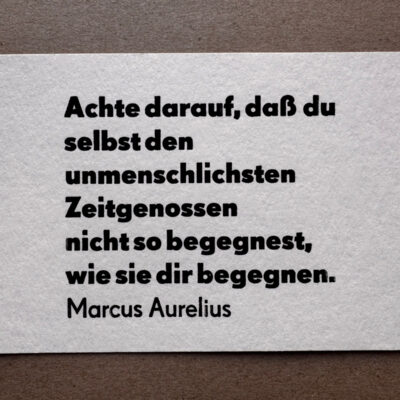Letterpress Postkarte mit Marcus Aurelius Zitat in schwarzer Super Groteske auf weißem Büttenpapier: 'Achte darauf, daß du selbst den unmenschlichsten Zeitgenossen nicht so begegnest, wie sie dir begegnen.' Siebenzeilig im traditionellen Handsatz ausgeführt.